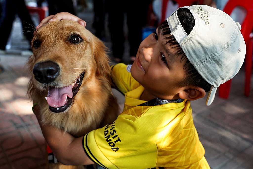 A child hugs Tualek, a dog of the K9 USAR Thailand, as search and rescue operations continue, following a strong earthquake, in Bangkok, Thailand, April 1, 2025. REUTERS/Chalinee Thirasupa