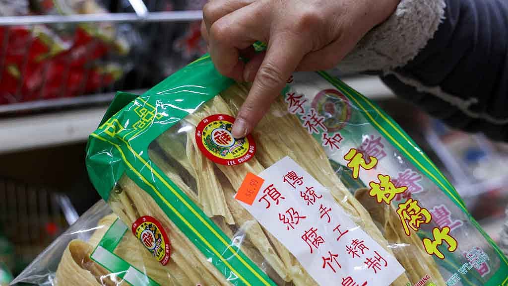 Sun Vin Grocery Manager Jasmine Bai points at the packaging and price of dried bean curd imported from China at the store in Chinatown in New York City, US, Apr 16, 2025. REUTERS/Kylie Cooper