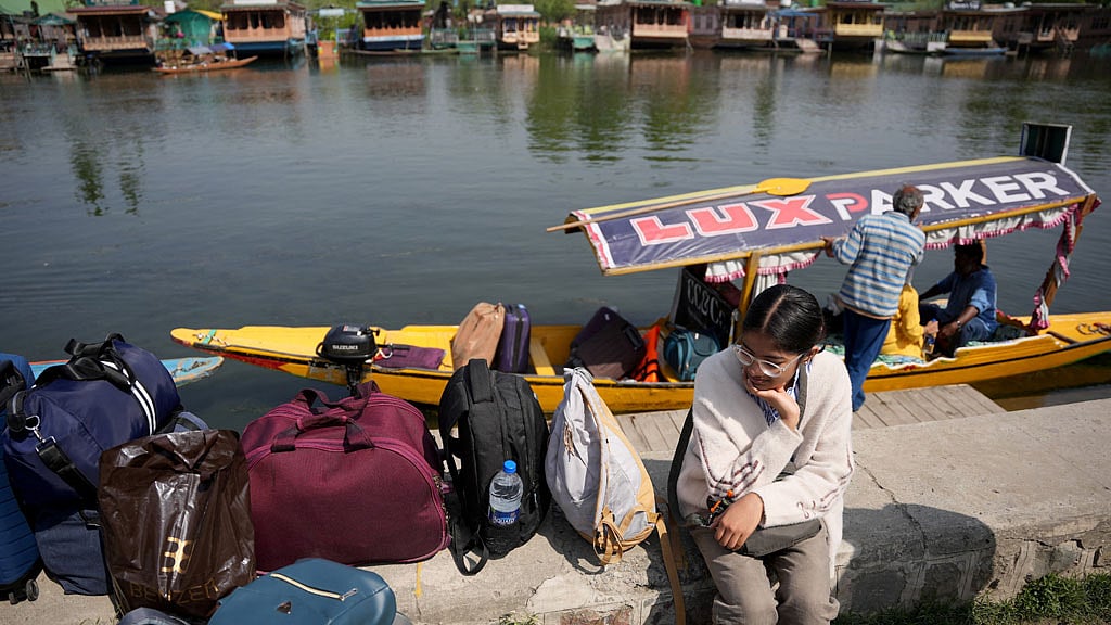 A tourist sits on the banks of Dal Lake with her belongings as she waits for transport to leave for Srinagar airport, following a suspected militant attack near south Kashmir’s scenic Pahalgam, Apr 23, 2025. REUTERS