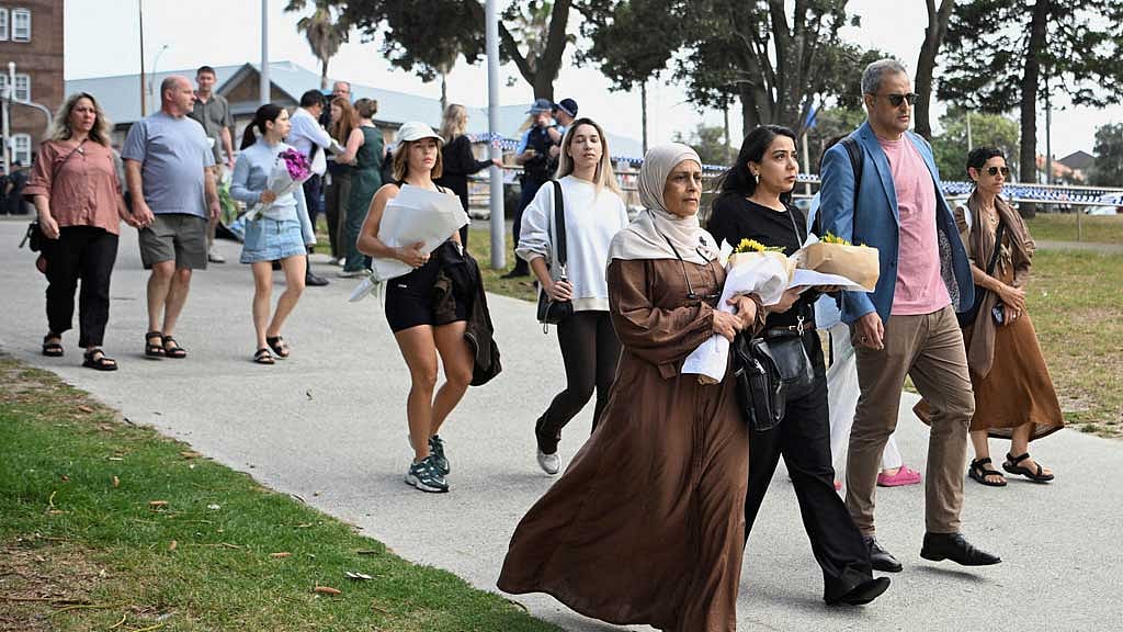 People bring flowers for a makeshift memorial following the attack on a Jewish holiday celebration at Sydney's Bondi Beach, in Sydney, Australia, Dec 15, 2025. REUTERS/Flavio Brancaleone