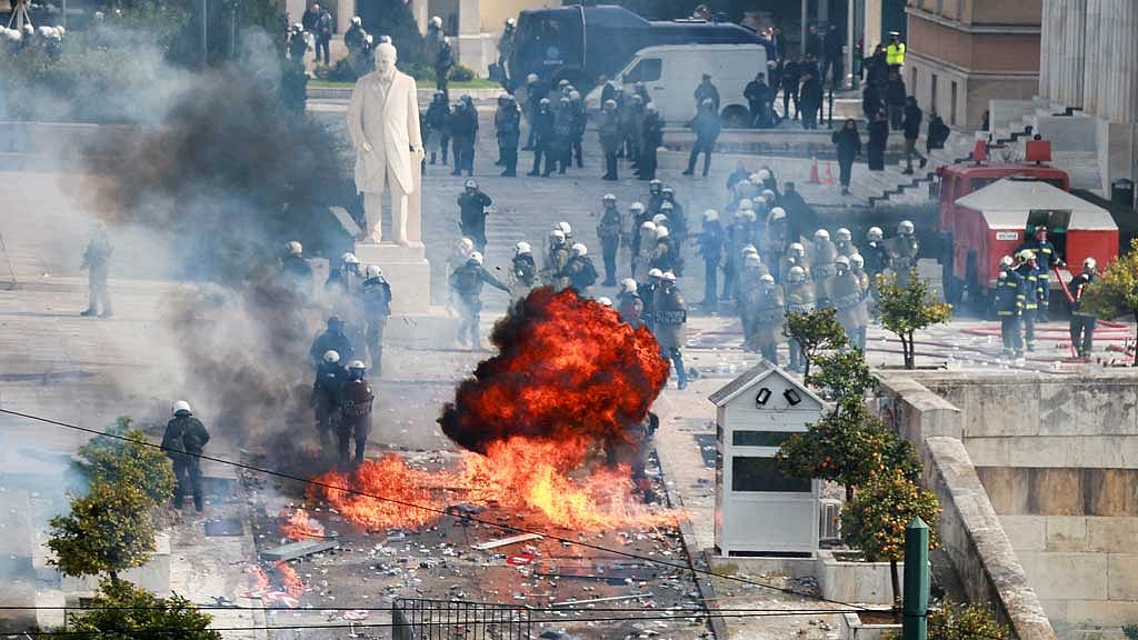 Police stand next to fire during clashes near the Greek parliament at a protest marking the second anniversary of the country's worst railway disaster, while an investigation continues, in Athens, Greece, Feb 28, 2025. REUTERS/Louiza Vradi