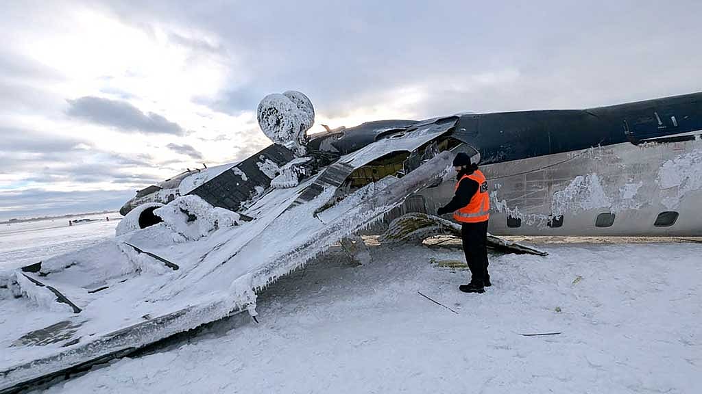 An investigator with Canada’s Transportation Safety Board (TSB) views the wreckage of a Delta Air Lines operated CRJ-900 aircraft lies crashed on the runway at Toronto Pearson International Airport in Mississauga, Ontario, Canada Feb 18, 2025. TSB/Handout via REUTERS  