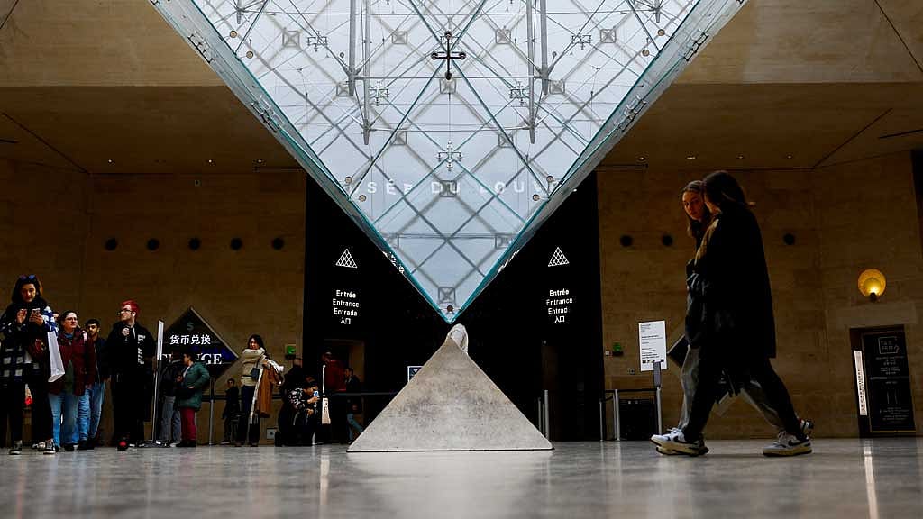 Tourists walk near the glass pyramid of the Louvre museum in Paris, France Jan 23, 2025. REUTERS/Gonzalo Fuentes