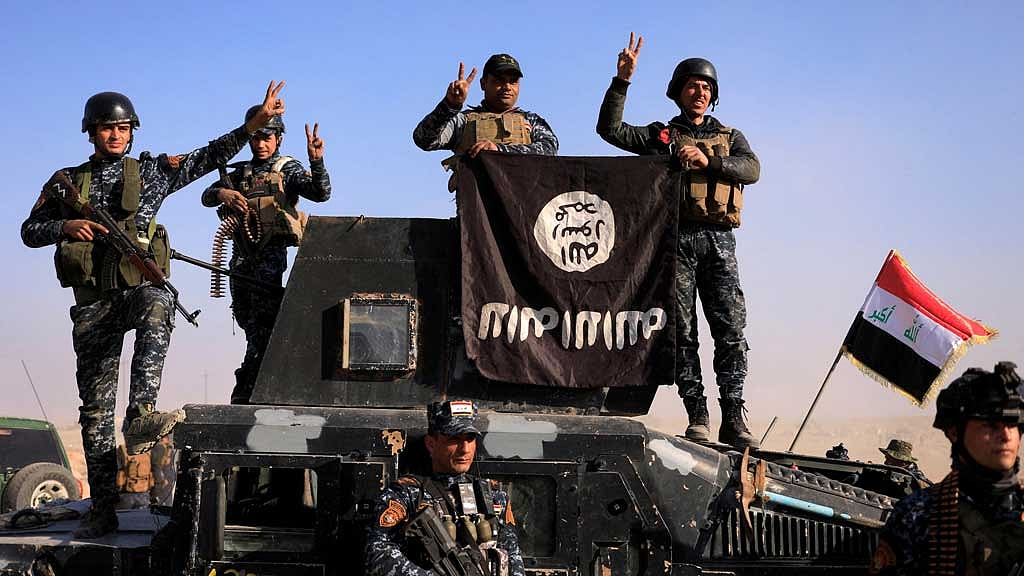 Federal police members pose with an Islamic State (IS) flag along a street of Albu Saif which was recaptured from Islamic State, south of Mosul, Iraq, February 22, 2017. REUTERS