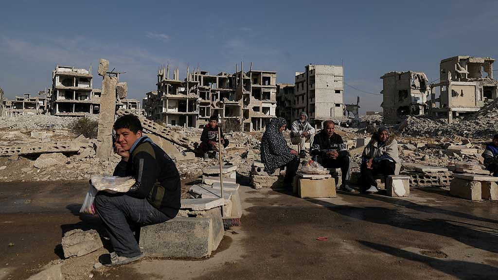 FILE PHOTO: People sit after receiving bread from Ecir Kapici, Turkish humanitarian NGO at al-Yarmouk Palestinian refugee camp, after Syria's Bashar al-Assad was ousted, in Damascus, Syria, Dec 20 , 2024. REUTERS/Zohra Bensemra/File Photo