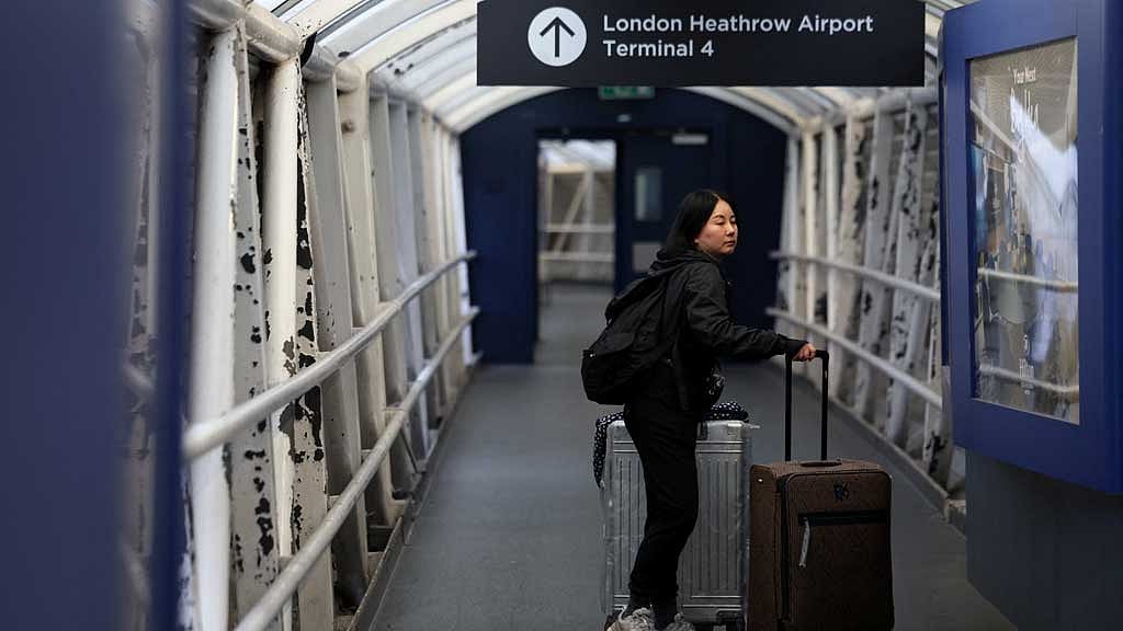 A passenger with luggage walks in a passage leading to Terminal 4 of Heathrow International Airport, after a fire at an electrical substation wiped out power at the airport, in London, Britain, Mar 21, 2025. REUTERS/Isabel Infantes