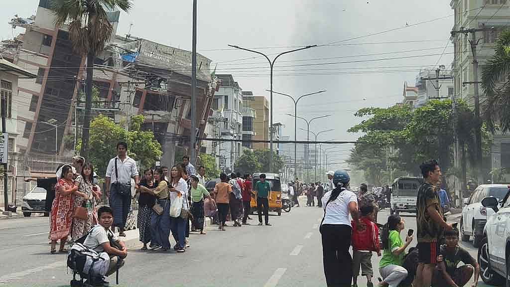 People gather on a street near damaged buildings after a strong earthquake struck central Myanmar, in Mandalay, Myanmar, March 28, 2025. REUTERS
