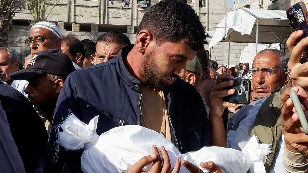 A man carries the dead body of a child as he attends the funeral of Palestinians killed in Israeli strikes, in Khan Younis, southern Gaza Strip, May 3, 2025. REUTERS/Hatem Khaled