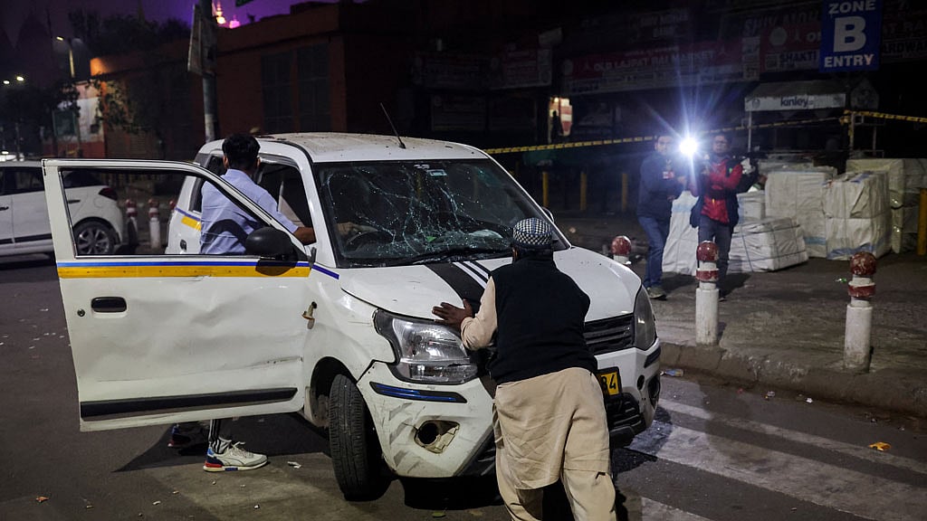 People push a damaged vehicle at the site of an explosion in the old quarters of Delhi, India, Nov 10, 2025.
