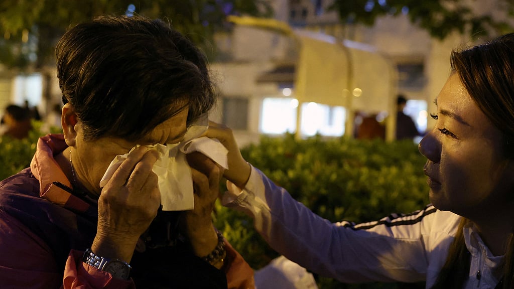 Michelle Liu, a social worker and counsellor, helps Cheung Yuk-ling, 73, who survived the deadly fire at the Wang Fuk Court housing complex, wipe her tears in Hong Kong, China, November 28, 2025. REUTERS