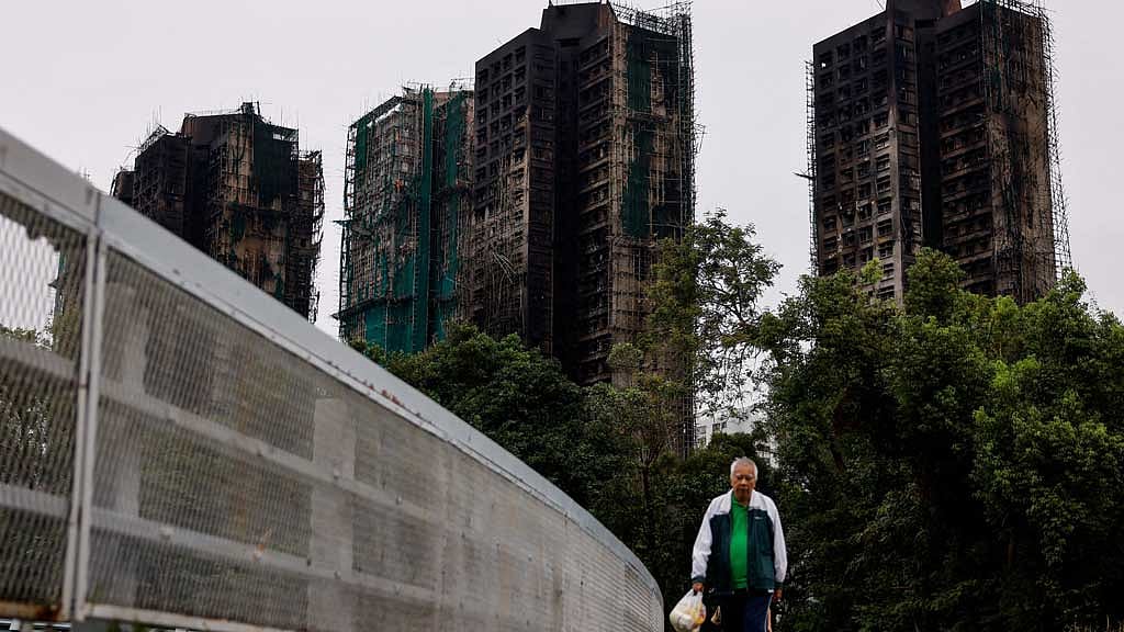An elderly man walks next to burned buildings of the Wang Fuk Court housing complex after the deadly fire, in Tai Po, Hong Kong, China, Nov 30, 2025. REUTERS/Maxim Shemetov