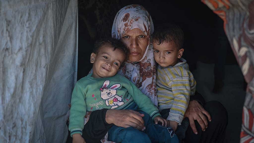 Displaced Palestinian mother Iman Abdel Halim Abu Mutlaq holds her twin sons Uday and Hamza Abu Odah at their tent where they shelter, in Mawasi area, in Khan Younis in the southern Gaza Strip, September 18, 2025. REUTERS