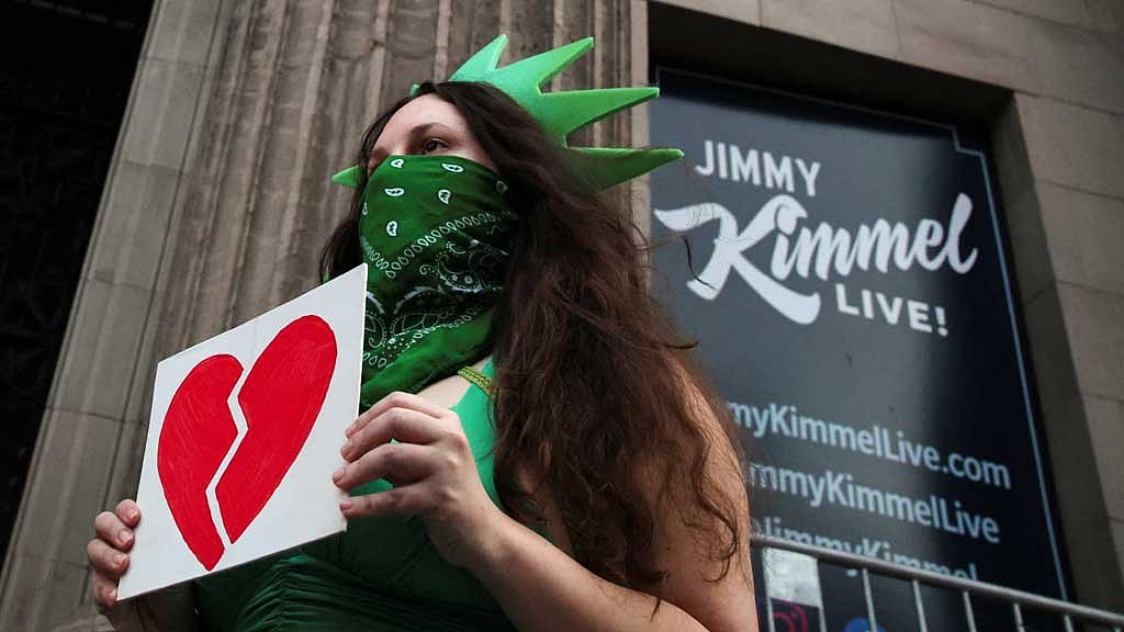 A woman wears a Statue of Liberty costume as she holds an image of a broken heart, outside the El Capitan Entertainment Centre, where "Jimmy Kimmel Live!" is recorded for broadcast, on Hollywood Boulevard in Los Angeles, California, US Sept 17, 2025. REUTERS/Daniel Cole
