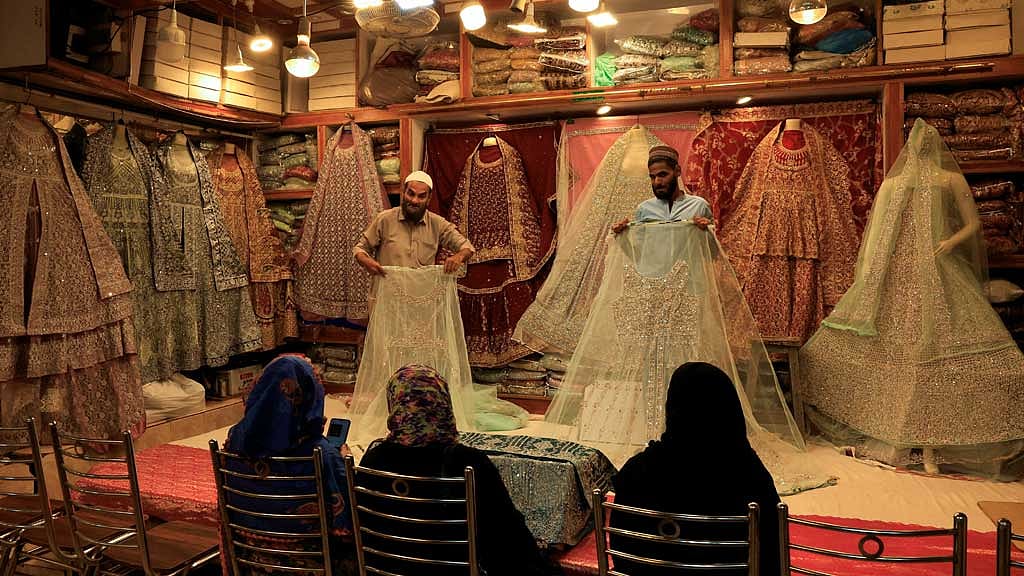 Shopkeepers display bridal dresses to customers at a shop in a cloth market in Karachi, Pakistan Sept 23, 2025. REUTERS