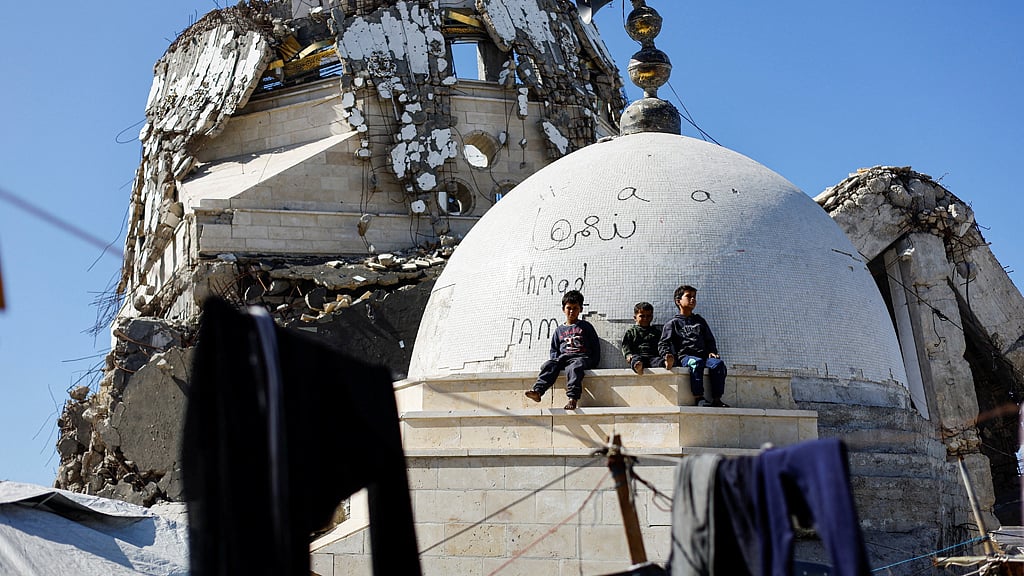 Palestinian children sit atop the rubble of a mosque destroyed during the two-year Israeli offensives, which is surrounded by tents for displaced Palestinians, in Gaza City, Feb 11, 2026. REUTERS/Mahmoud Issa