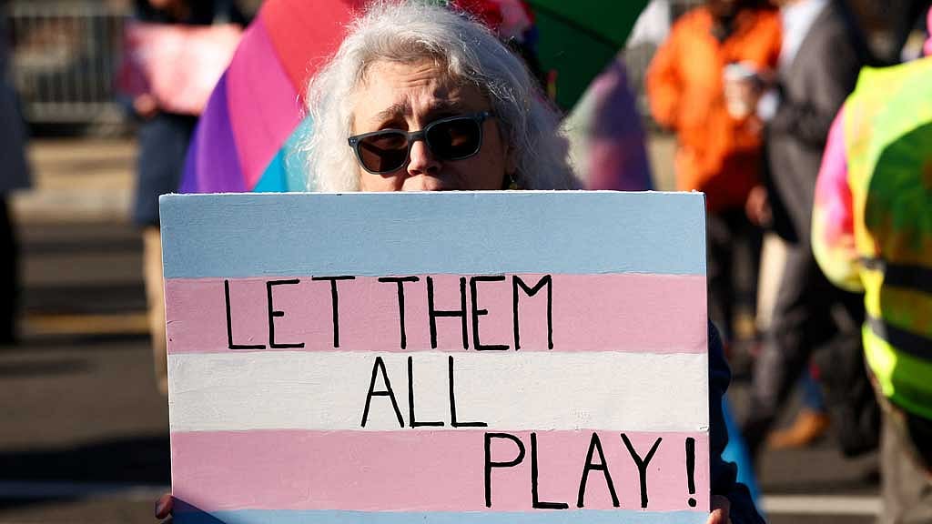 A transgender rights supporter holds a placard while demonstrating on the day justices are expected to hear oral arguments in two cases concerning efforts to enforce Republican-backed state laws banning transgender athletes from female sports teams at public schools, outside the US Supreme Court in Washington, DC, Jan 13, 2026. REUTERS