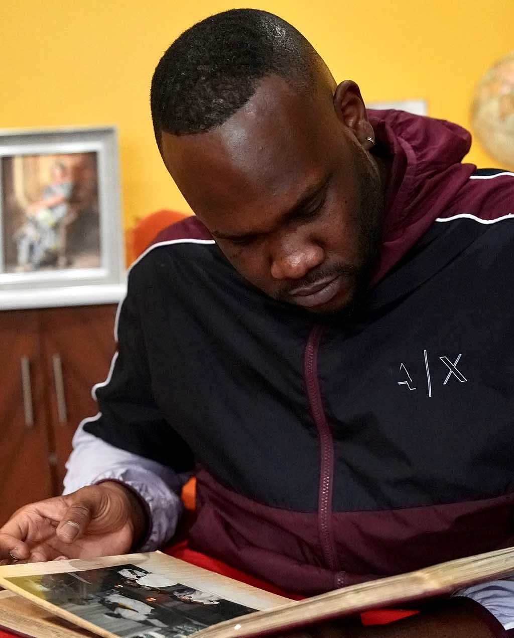 Mohamed Alghali, 33, looks at an album containing photographs of his mother, Rabbiatu Kuyateh, at the home they shared in Bowie, Maryland, US, Dec 10, 2025. Kuyateh was deported in November to Ghana, which has an agreement with the Trump administration to take West African migrants who cannot easily be sent to their home countries. She said she was then flown against her will to her native Sierra Leone, where she feared she could be tortured because of her father's ties to the political opposition. REUTERS