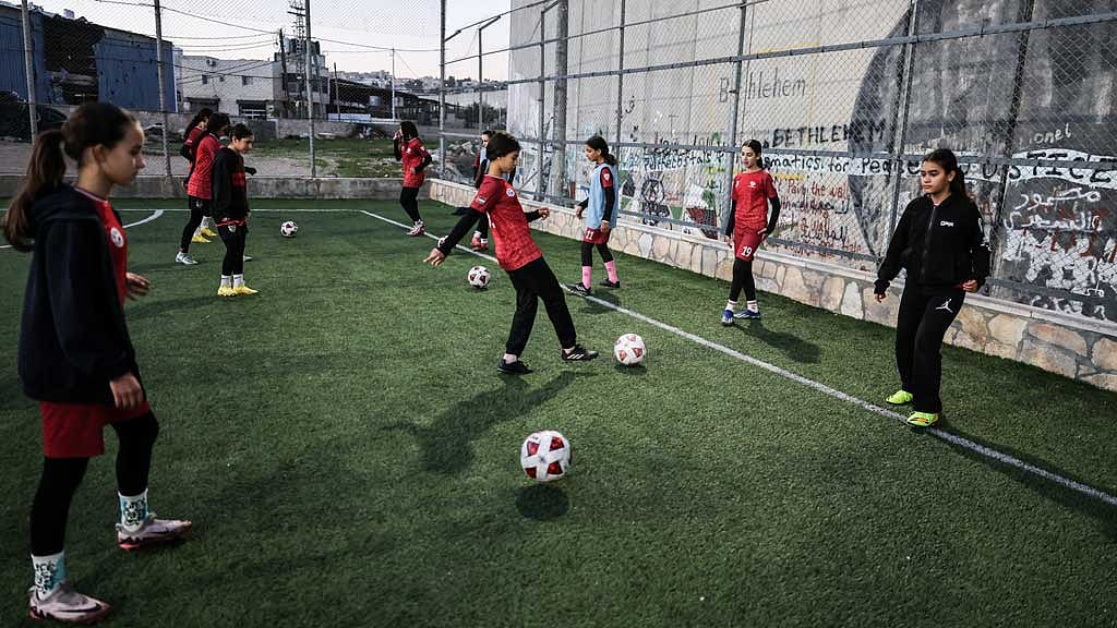 Palestinian camp team plays football in a field next to West Bank barrier separating Aida refugee camp from Jerusalem, in the Israeli-occupied city of Bethlehem, Jan 11, 2026. REUTERS/Ammar Awad