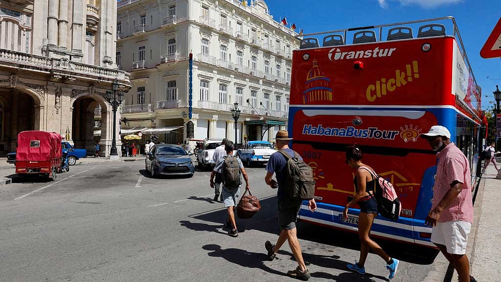 Tourists cross a street near a hop-on hop-off sightseeing bus as US sanctions have led most major tourism and travel companies to leave the island or drastically scale back their operations, in Havana, Cuba Jun 8, 2026. REUTERS/Norlys Perez
