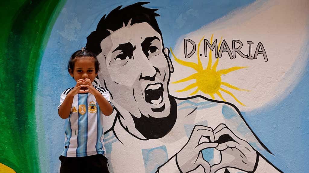 A young girl wearing an Argentine jersey displays a heart sign next to a mural depicting Argentine soccer player Angel Di Maria, ahead of the 2026 FIFA World Cup, in Dhaka, Bangladesh, Jun 9, 2026. REUTERS/Mohammad Ponir Hossain