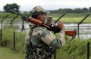 An Indian Border Security Force (BSF) soldier keeps watch along the fenced border with Bangladesh in Fulbari village, on the outskirts of Siliguri. Photo: Reuters. 