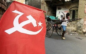 A rickshaw puller moves past a flag of the Communist Party of India. Photo: Reuters 