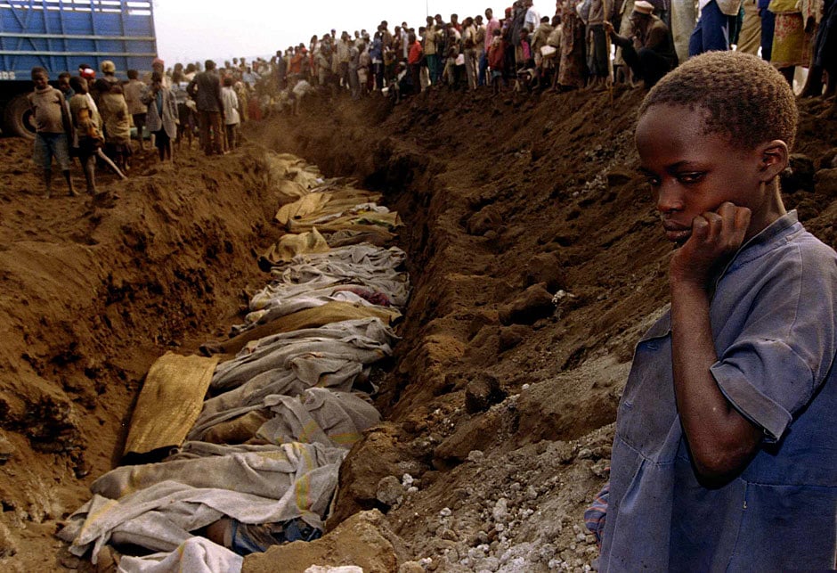 A Rwandan refugee girl stares at a mass grave where dozens of bodies have been laid to rest July 20, 1994. Rwandan refugees who escaped from fighting between government troops and RPF rebels died by the hundreds of dehydration, lack of food, and cholera. REUTERS/Corinne Dufka. 