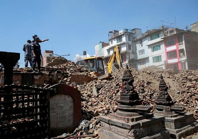 Nepalese police personnel look on as an excavator is used to dig through rubble to search for bodies following the earthquake in Kathmandu, Nepal. REUTERS/DANISH SIDDIQUI. 