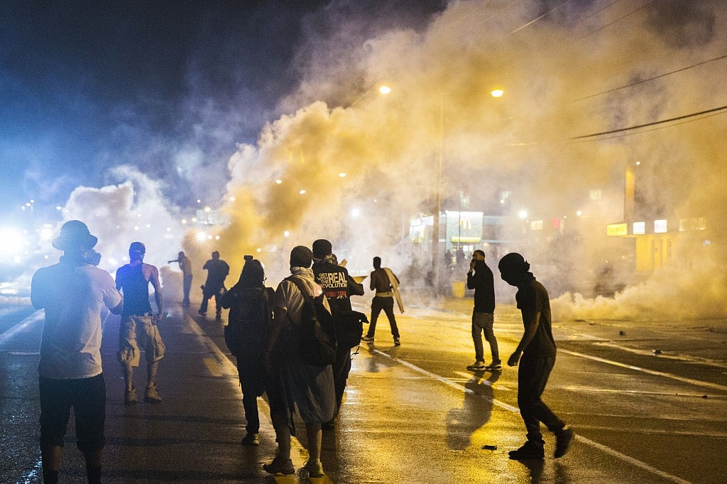 Protesters walk through smoke as police clear a street after the passing of a midnight curfew meant to stem ongoing demonstrations in reaction to the shooting of Michael Brown, in Ferguson, Missouri August 17, 2014. REUTERS/Lucas Jackson 
