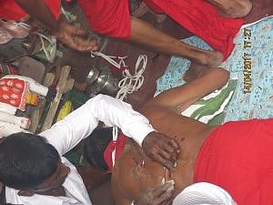 অদূরে একটি শিবের মন্দিরে 'সন্ন্যাসী'র পিঠে হুক বিদ্ধ করা হচ্ছে। 