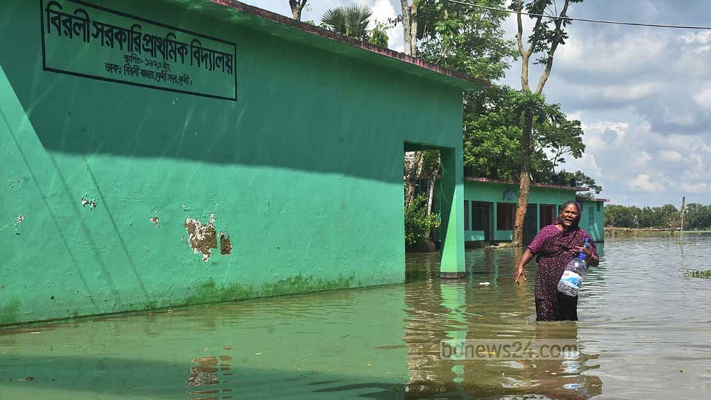 ফেনীর সদর উপজেলার বিরলী গ্রামের হাই স্কুলের দুই তলায় আশ্রয় নিয়ে আছে মাজেদা বেগমের পরিবার। ত্রাণ নিতেও তাদের হাঁটু সমান পানি ভেঙে বের হতে হচ্ছে। বৃহস্পতিবার সুমন বাবুর তোলা ছবি।