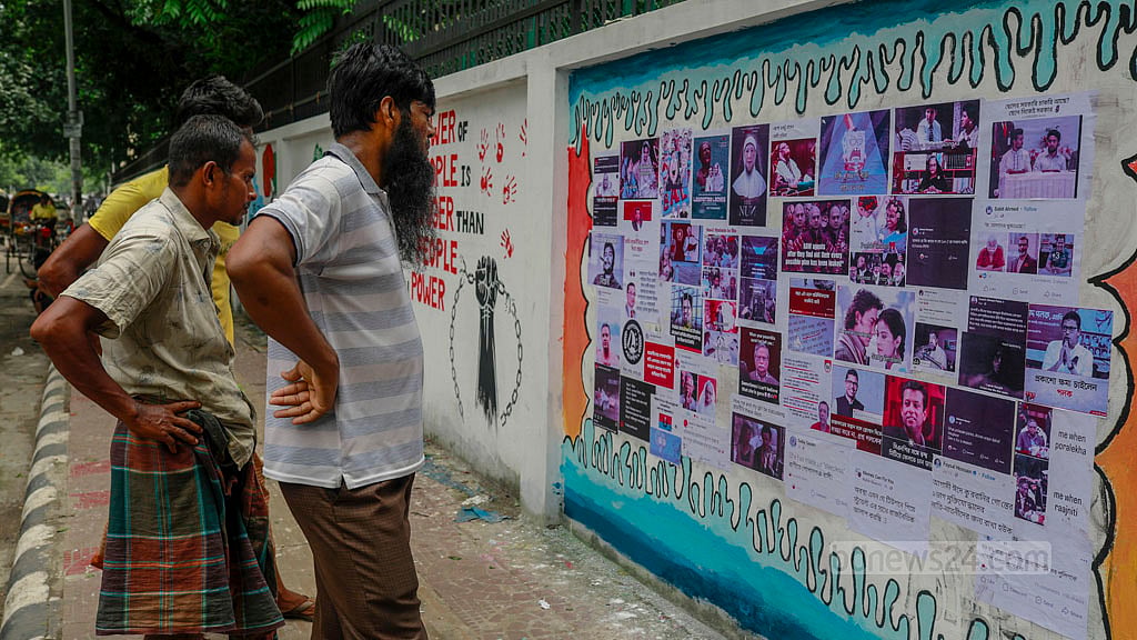 এস এম হলের বিপরীত পাশে বুয়েটের দেয়ালে লাগিয়ে দেওয়া হয়েছে কোটা সংস্কার আন্দোলনের বেশকিছু আলোকচিত্র, সেগুলো দেখছেন পথচারীরা। 