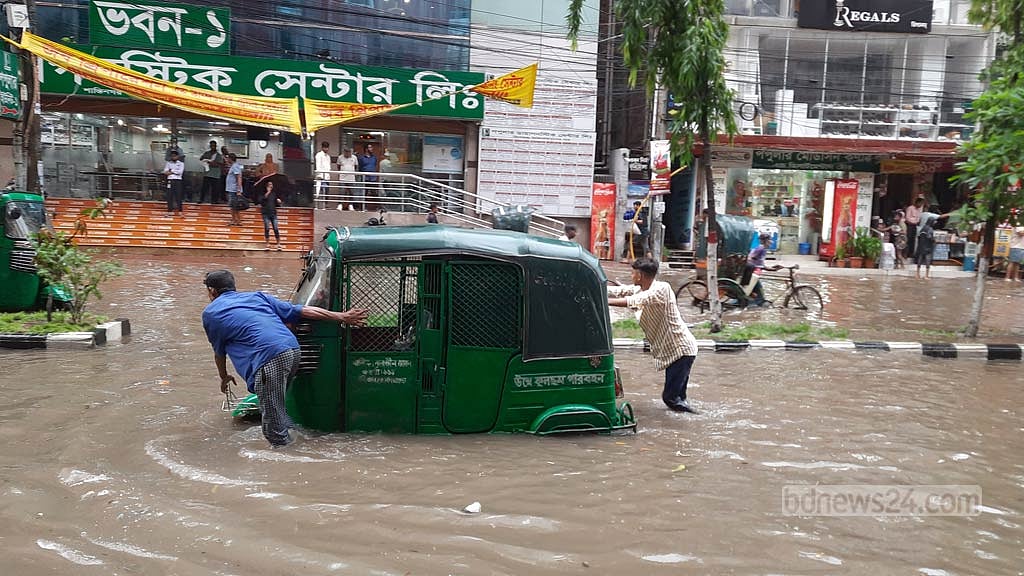 জমে যাওয়া বৃষ্টির পানিতে নষ্ট অটোরিকশা নিয়ে বিপাকে চালক। শুক্রবার সকালে রাজধানীর শান্তিনগরের চিত্র। ছবি: সুমন মাহমুদ