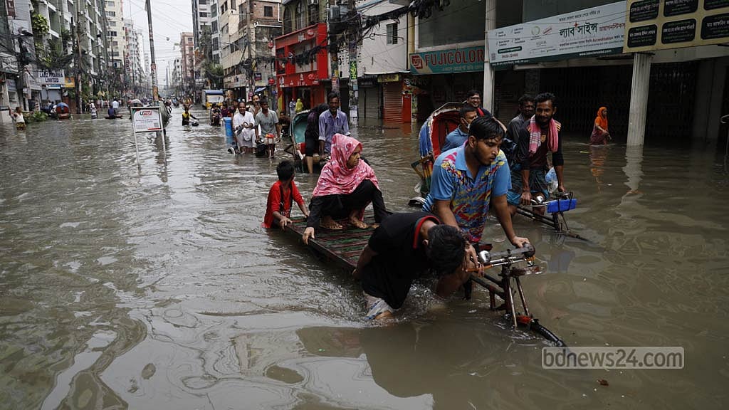 ভারি বৃষ্টিতে শুক্রবার রাজধানীর গ্রিন রোডে কোমর সমান পানি জমে গেলে রিকশা-ভ্যানে করে পাড়ি দিতে দেখা যায় অনেককে। ছবি: মাহমুদ জামান অভি