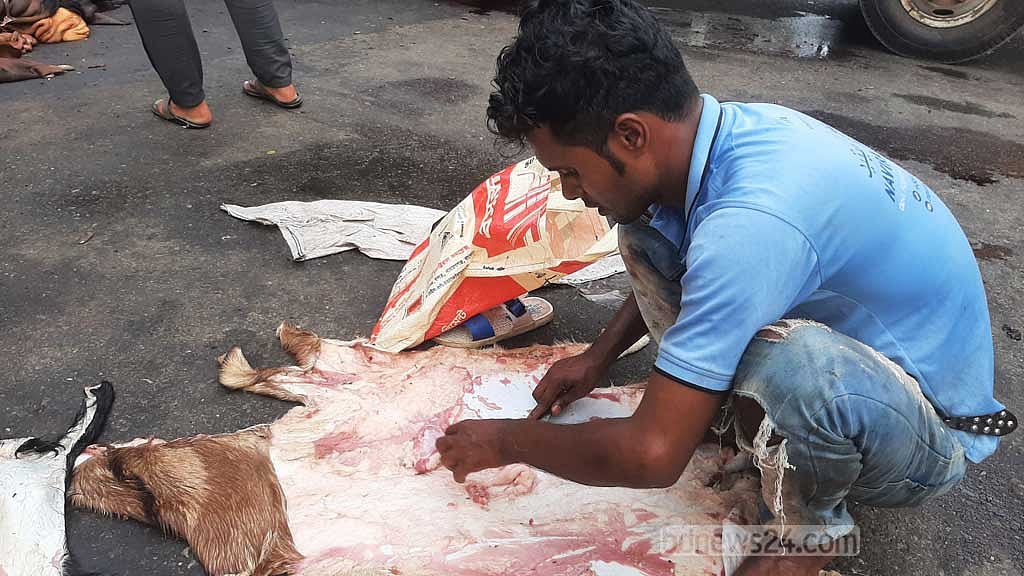 গুলশান এলাকায় সড়কের চামড়া ফেলে মাংস ছাড়াচ্ছেন অখিল। 