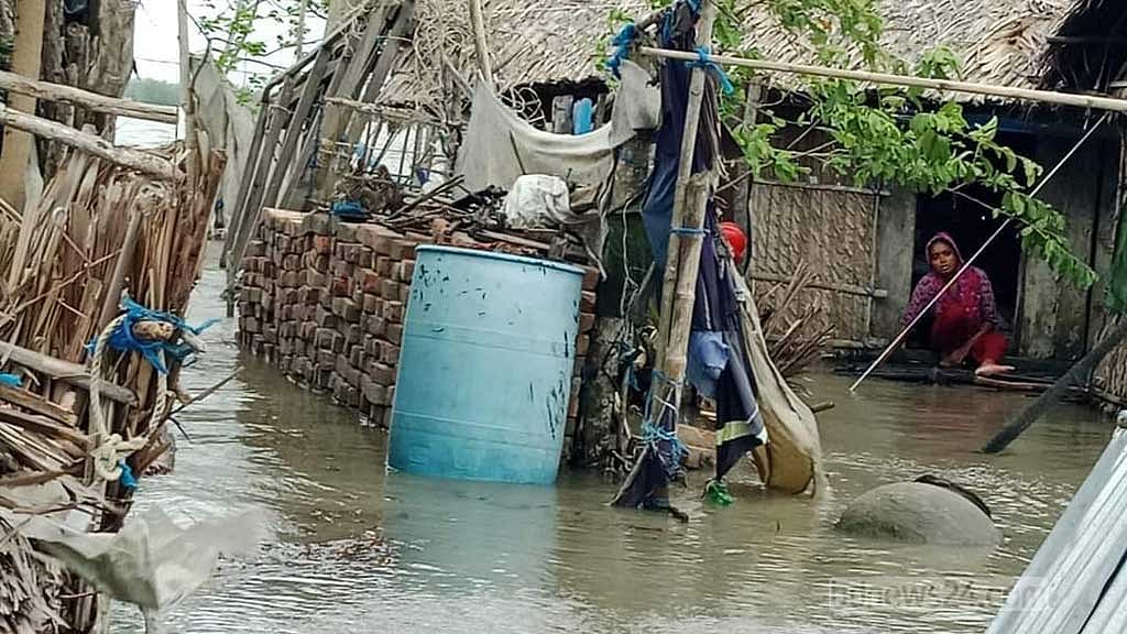 খুলনার দাকোপ উপজেলার সুতারখালি এলাকার ঝুলন্ত পাড়ায় ডুবে যাওয়া বাড়ির দরজায় বসে আছেন অসহায় এক নারী।