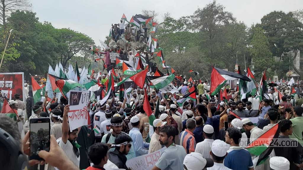 ‘মার্চ ফর গাজা’ কর্মসূচিতে অংশ নিতে আসা অনেকে ফিলিস্তিনের পতাকা হাতে উঠে পড়েন সোহরাওয়ার্দী উদ্যান সংলগ্ন ঢাকা বিশ্ববিদ্যালয়ের রাজু ভাস্কর্যেওর ওপরে।