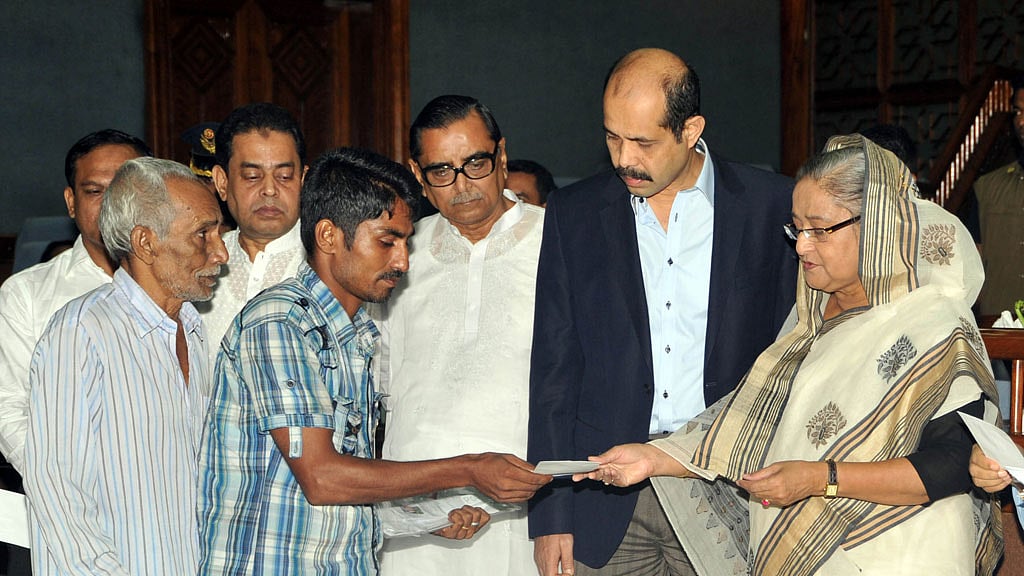 Former prime minister Sheikh Hasina hands over cheques to 175 affected families of the Rana Plaza collapse at an event on Jul 24, 2013.