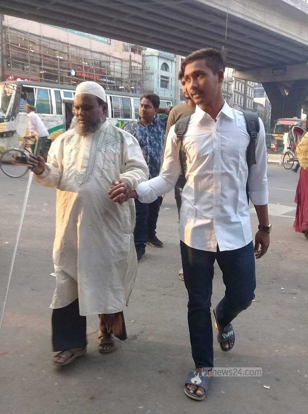 Wasim Akram helping a man with visual impairment to cross the road.