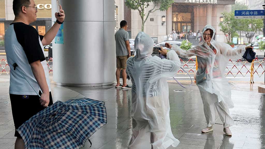সাংহাইয়ের বাসিন্দারা ঝড়-বৃষ্টির মধ্যে ছবি তুলছেন। ছবি: রয়টার্স