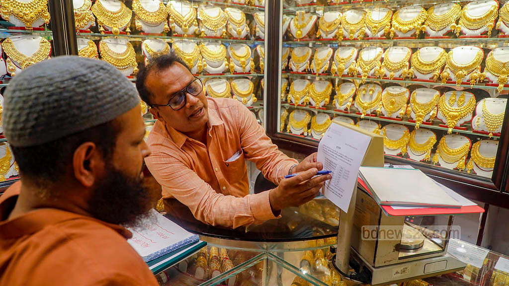 সোনার গহনা কিনতে এসে দাম শুনে হিমশিম খাচ্ছেন ক্রেতারা। তাদের বর্তমান মূল্যে তালিকা দেখাচ্ছেন বায়তুল মোকারম মার্কেটের এক দোকানি।  ছবি: আব্দুল্লাহ আল মমীন