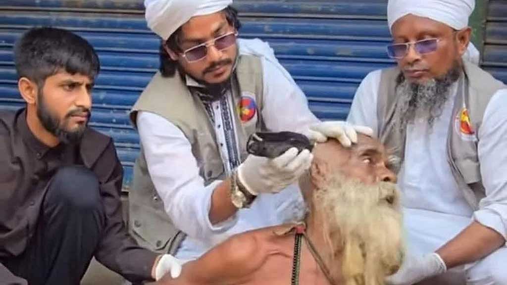 সম্প্রতি সামাজিক মাধ্যমে ছড়িয়ে পড়া ভিডিওটি থেকে নেওয়া ছবি। এখানে কয়েকজন মিলে প্রকাশ্যে একজন বৃদ্ধের চুল কেটে দিচ্ছেন। এই বৃদ্ধ কোনো ভবঘুরে নন, তিনি ওই এলাকারই বাসিন্দা এবং পরিবারের সদস্য।