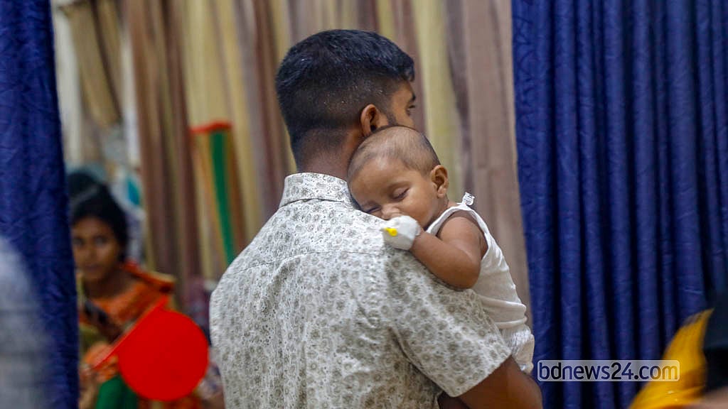 হামে আক্রান্ত সন্তানকে কোলে নিয়ে রাজধানীর মুগদা মেডিকেল কলেজ হাসপাতালের ওয়ার্ডের মধ্যে ঘুরছেন এক বাবা। ছবি: আব্দুল্লাহ আল মমীন