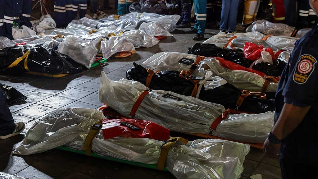 ব্যাংককে বারে ভয়াবহ আগুনে নিহতদের মরদেহের পাশে জরুরি উদ্ধারকারী দলের সদস্যরা কাজ করছেন। ছবি: রয়টার্স