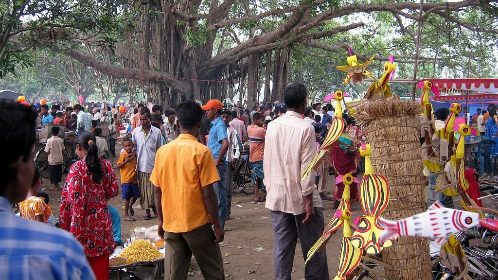 একপাশে রঙিন শামিয়ানা টাঙিয়ে বসেছে মিষ্টির দোকান। সেখানে মাটির চুলায় বড় কড়াইয়ে ফুটছে তেল, ছবি: লেখক।