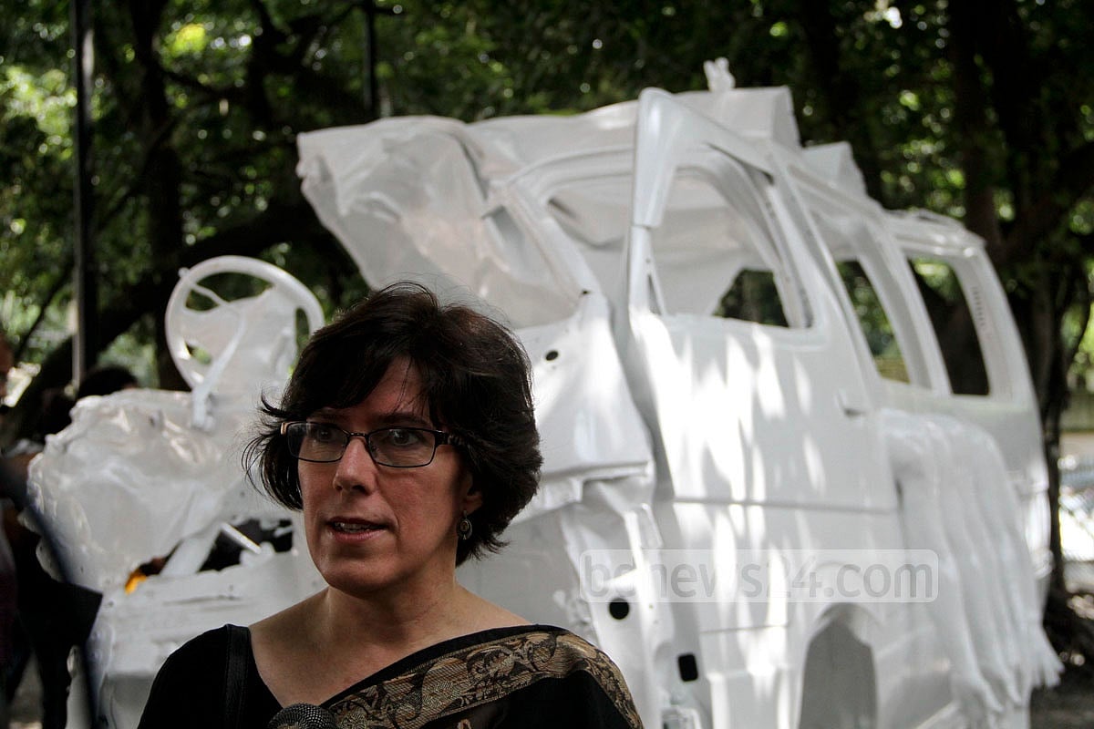 Catherine Masud in front of a memorial built out from the damaged car at the Dhaka University. 