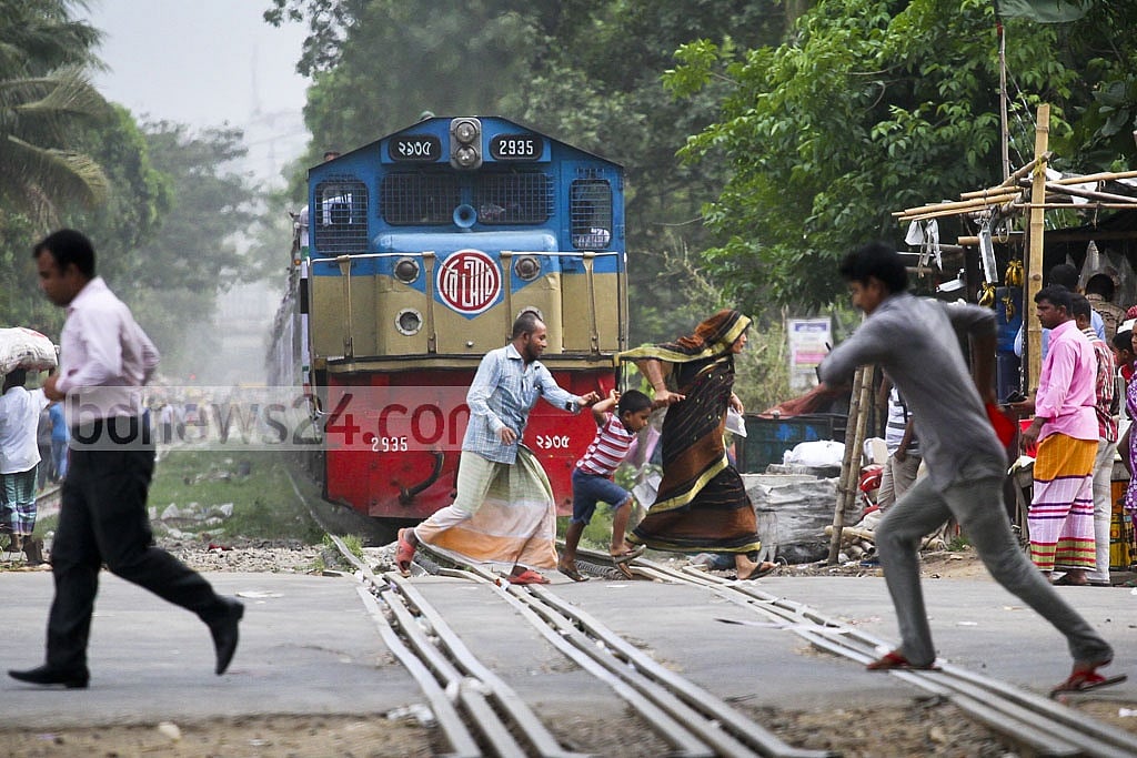 A train rushing in within arm’s reach as two pedestrians narrowly escape death while crossing the tracks with a child.