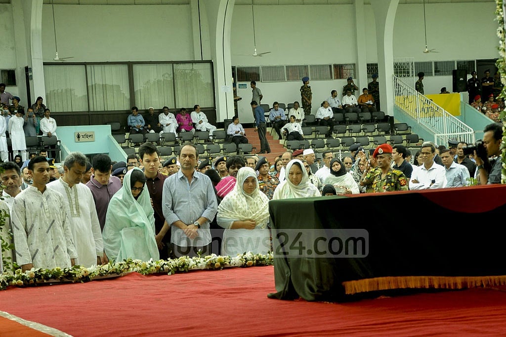 Family members of the attack's three Bangladeshi victims stand before their coffins.  