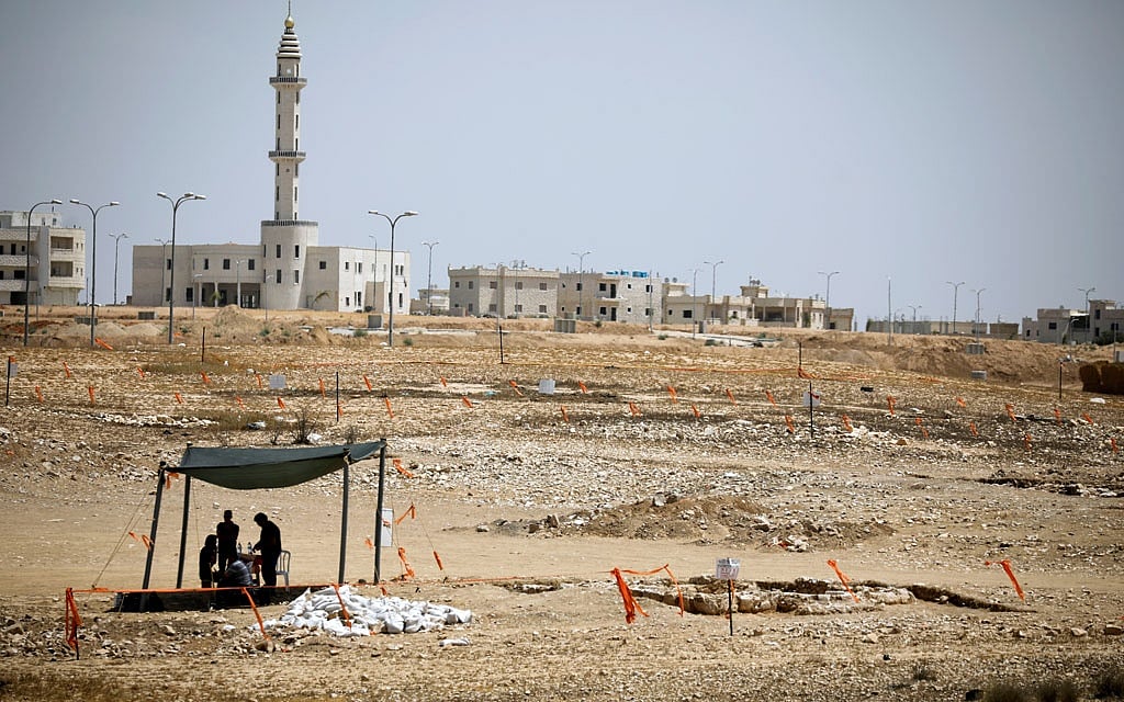 A mosque is seen in the background, as archaeology workers stand beneath a shade near the remains of a mosque (R), discovered by the Israel Antiquities Authority, which they say is one of the world's oldest, in the outskirts of the Bedouin town of Rahat in southern Israel July 18, 2019. Reuters 