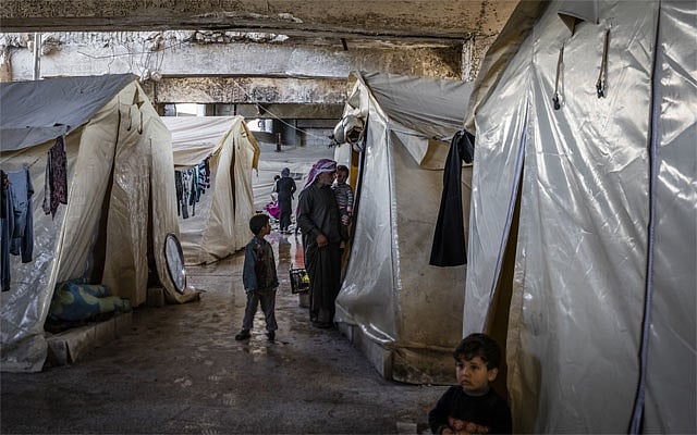 FILE -- Syrian families, displaced by recent fighting, living in tents underneath the stands of a sports stadium being used as an emergency shelter in Idlib, Syria, March 4, 2020. Crowded camps, depleted clinics and scarce soap and water make social distancing and even hand-washing impossible for millions of refugees. (Ivor Prickett/The New York Times) 